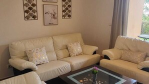 A living room with a beige sofa set, a coffee table with decorative stones, and three framed wall art pieces.