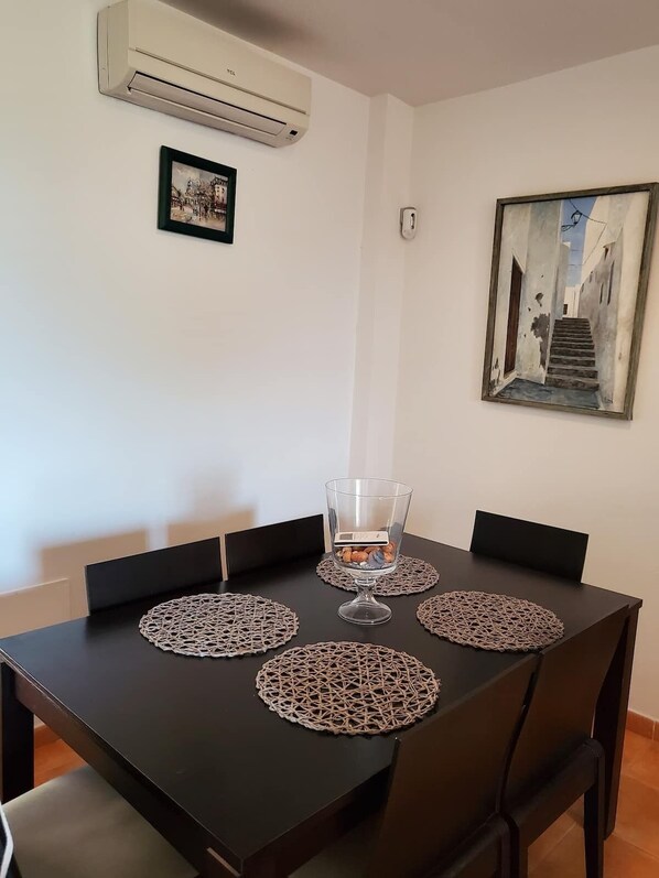A dining table with four chairs, a glass with a digital scale, and two framed artworks on the wall. - GROUND FLOOR WITH OWN GARDEN IN VALLE DEL ESTE GOLF!! (Vera)