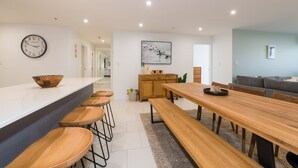 Une cuisine moderne avec un îlot central en bois, des tabourets de bar et une table à manger avec des bancs.