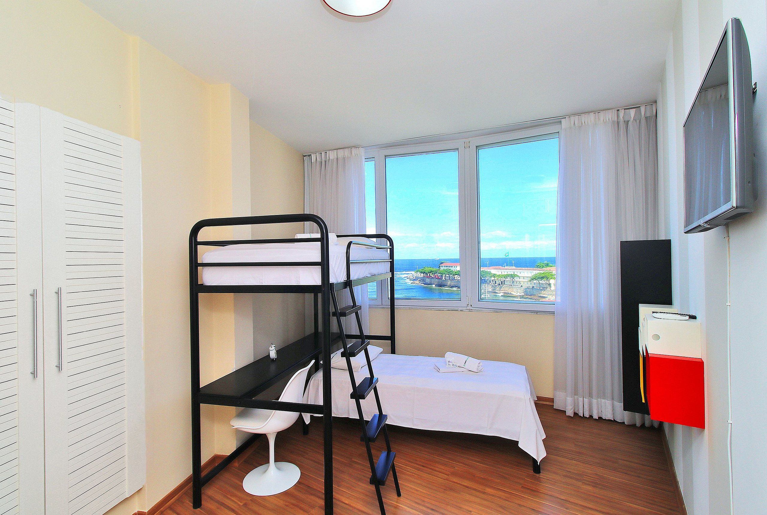Una habitación con literas, un escritorio, una silla, un televisor y una ventana con vistas.