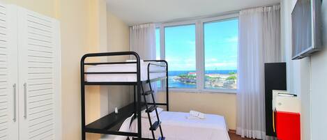 Una habitación con literas, un escritorio, una silla, un televisor y una ventana con vistas.