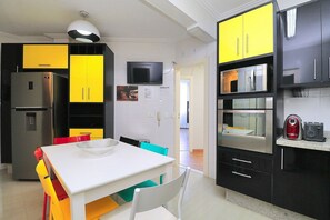 A modern kitchen with a dining area, including a refrigerator, microwave, and a flat-screen TV. - Rio Spot Homes T037 Ocean View (Rio de Janeiro)