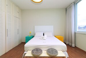 A neatly arranged bedroom with a bed, bedside tables, a wardrobe, and a window with curtains.
