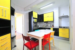 Une cuisine moderne avec des meubles de rangement jaunes et noirs, une table blanche et des chaises rouges.