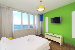 A hotel room with a bed, a TV, a desk, and a window with a view. - Rio Spot Homes T037 Ocean View (Rio de Janeiro)
