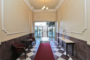 A hotel lobby with a checkered floor, a red carpet, a chandelier, and a statue. - Rio Spot Homes T037 Ocean View (Rio de Janeiro)