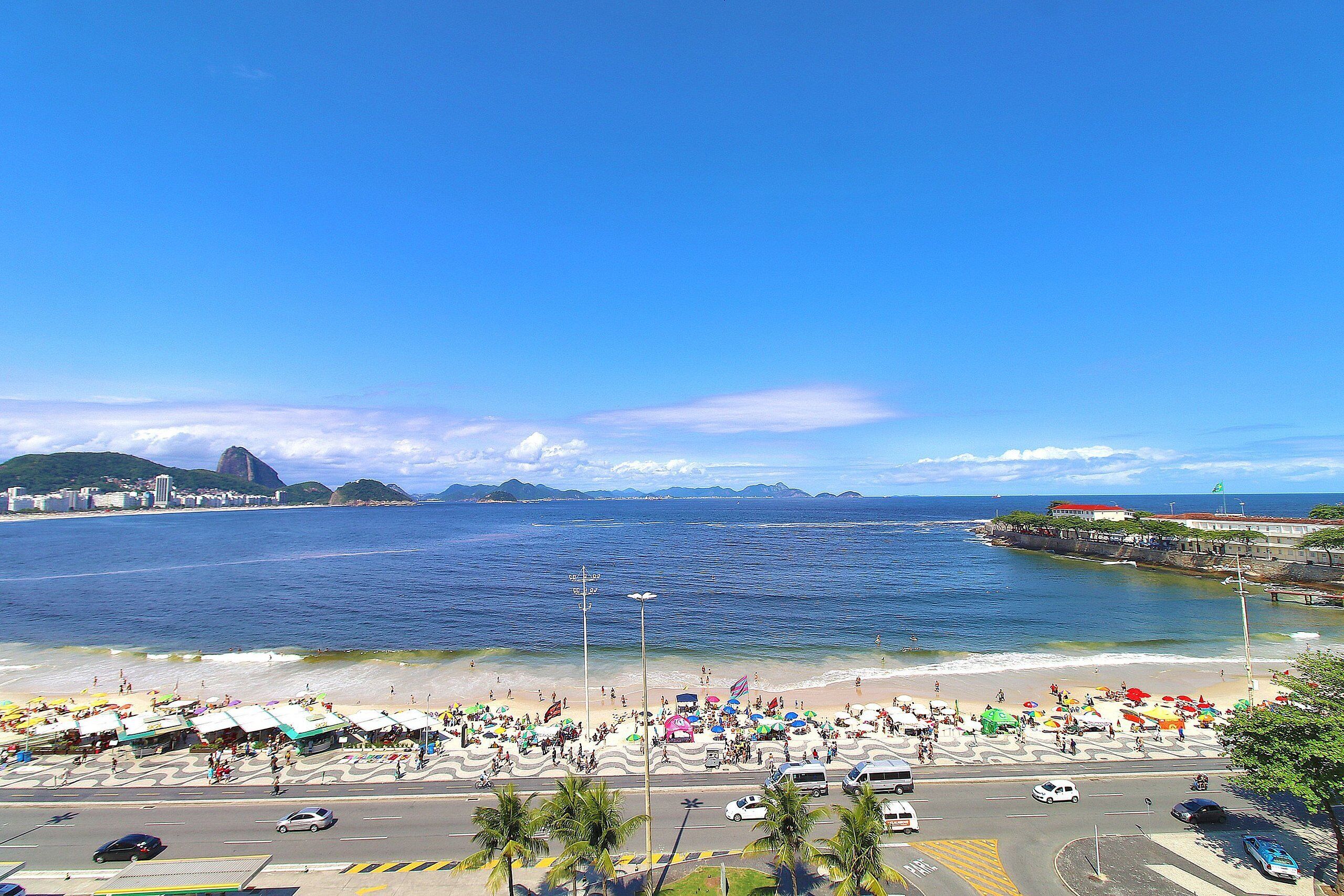 A beach with umbrellas, people, and a view of the ocean.