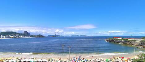 A beach with umbrellas, people, and a view of the ocean.