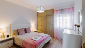 Una camera da letto con un letto, comodini, un armadio, uno specchio e una finestra con tende.
