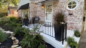 Ein Ziegelhaus mit einer Veranda, einem kleinen Garten und einem Schild, das zum Garten weist.