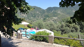 A pool area with a stone pathway, surrounded by greenery and overlooking a mountainous landscape. - Secluded private villa with pool close to the mountains, just 25 mins from Nice (Coaraze)