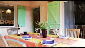 A dining table set with plates, glasses, and a bottle, surrounded by chairs and a potted plant. - Secluded private villa with pool close to the mountains, just 25 mins from Nice (Coaraze)