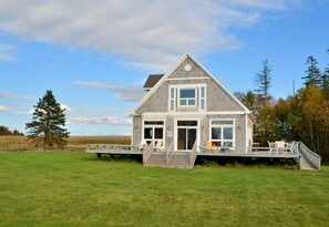 A two-story house with a deck, a staircase, and a large window.