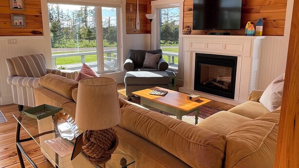 A cozy cabin interior with a wooden ceiling, a sofa, a television, and a fireplace.
