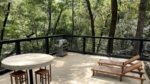 An outdoor deck with a round table, two wooden chairs, a grill, and two wooden lounge chairs. - Meadows MIll House II (Salem)