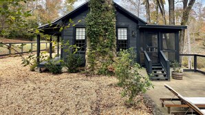 A cabin with a stone chimney, wooden siding, and a porch area. - Meadows MIll House II (Salem)