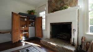 A cozy room with a stone fireplace, wooden cabinets, and a window with a view of greenery. - Meadows MIll House II (Salem)