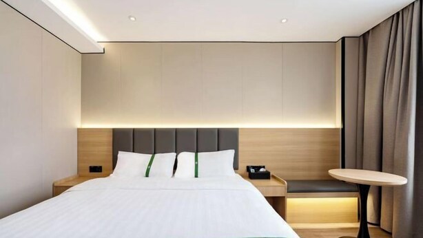 A hotel room with a bed, bedside tables, a small round table, and a bench. - GreenTree Inn Express Hotel (Shanghai Songjiang Sports Center Subway Station) (Shanghai)