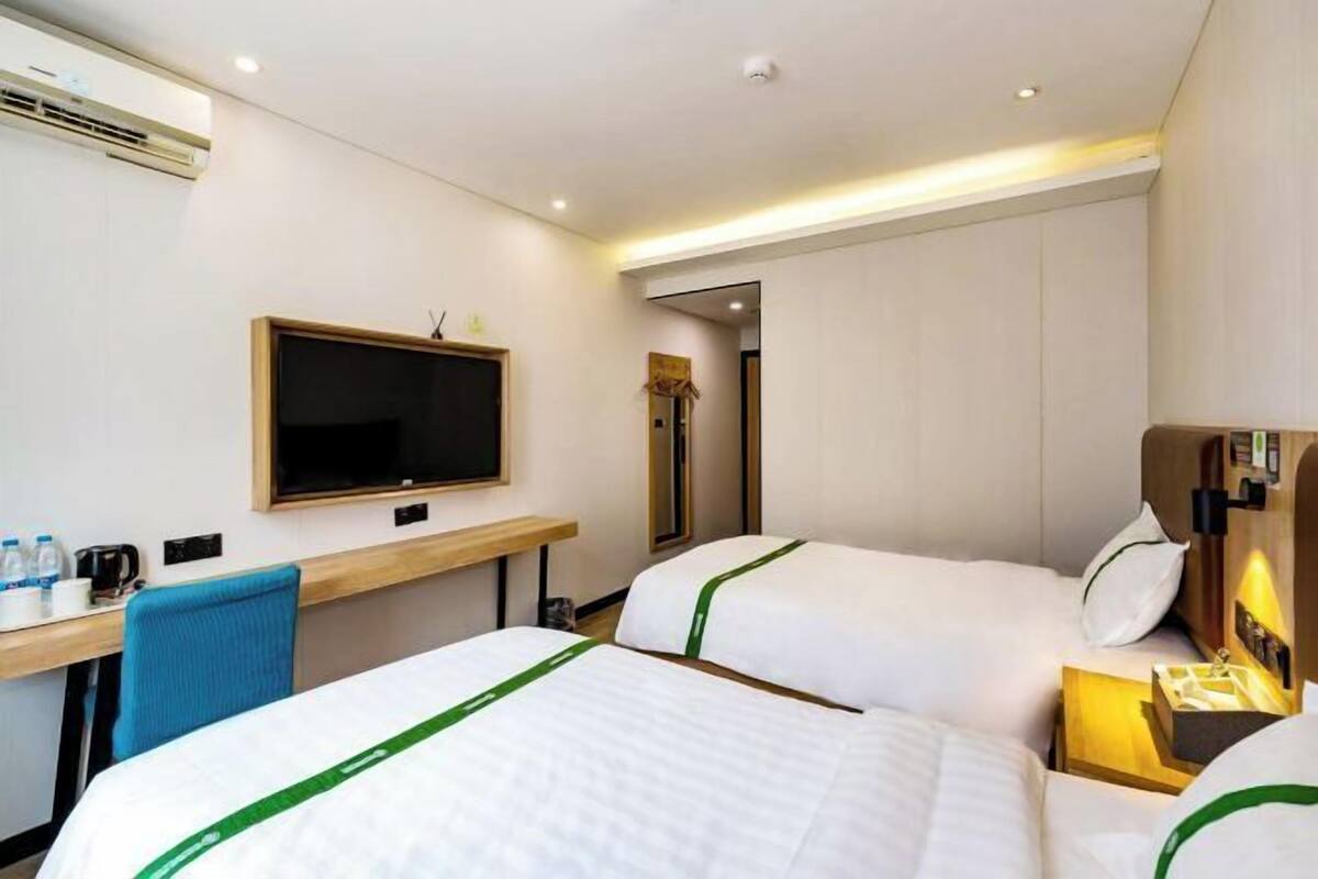 A hotel room with two beds, a desk, a television, and a minibar.