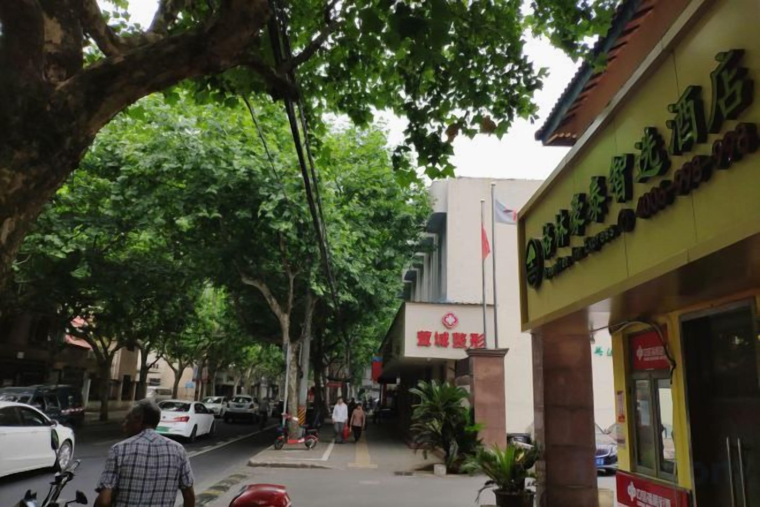 A street view with a building featuring a sign with Chinese characters, a red flag, and a pedestrian crossing.