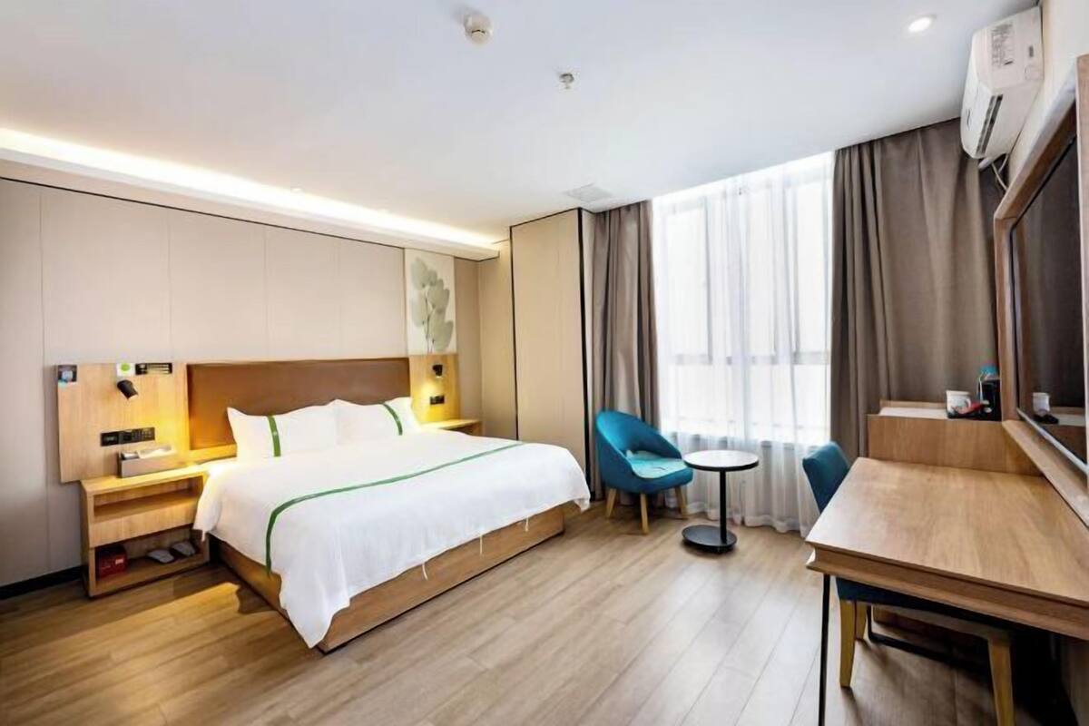 A hotel room with a bed, a desk, a chair, and a small table.