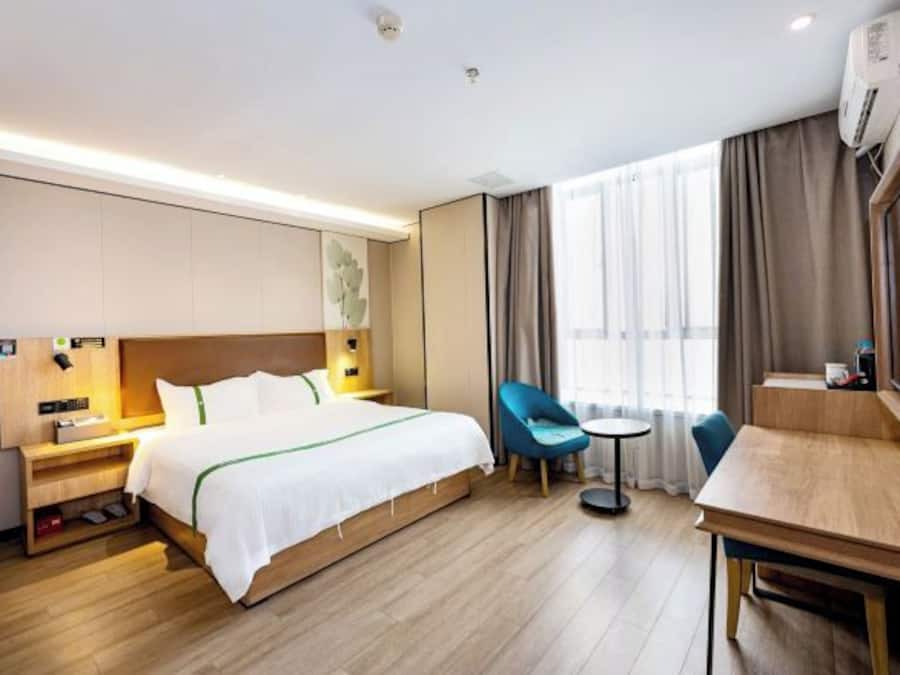 A hotel room with a bed, a desk, a chair, and a small table.