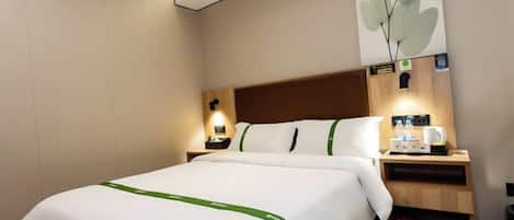 Habitación de hotel con cama, mesitas de noche y una cafetera de pared.