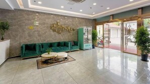 A spacious lobby with a green sofa, a coffee table, and a reception desk. - GreenTree Inn Express Hotel (Shanghai Songjiang Sports Center Subway Station) (Shanghai)