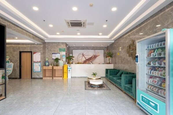 A hotel lobby with a reception desk, seating area, and vending machine. - GreenTree Inn Express Hotel (Shanghai Songjiang Sports Center Subway Station) (Shanghai)