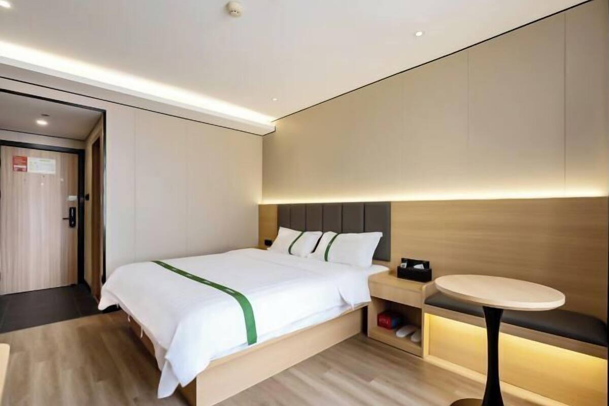 A modern hotel room with a bed, bedside table, and a small round table.