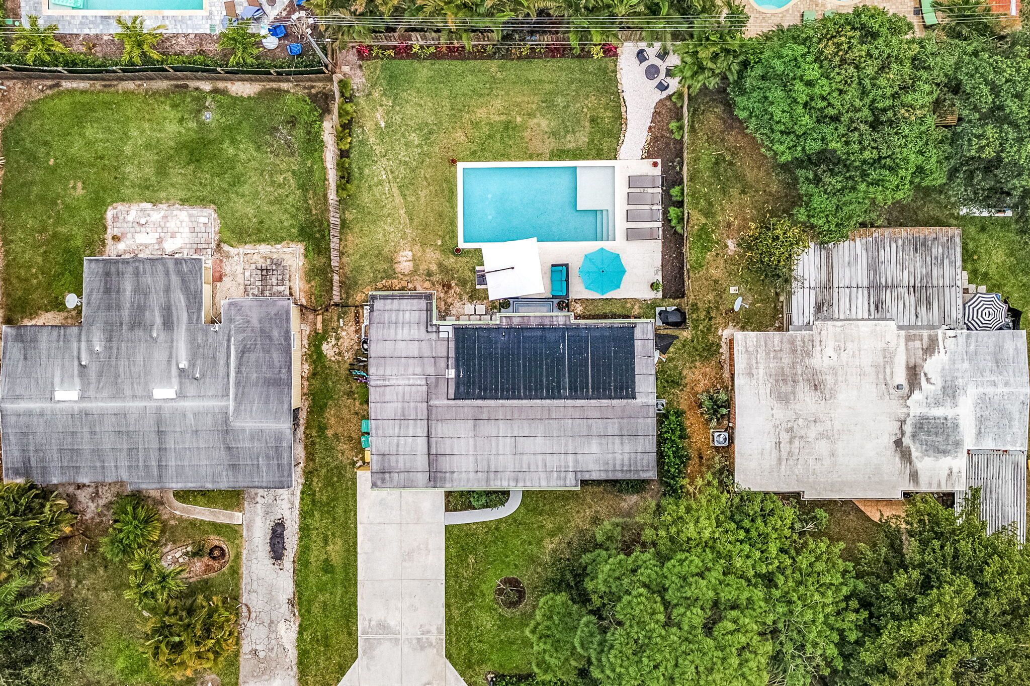 An aerial view of a residential property with a swimming pool, solar panels, and a covered patio area.