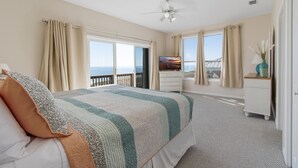 Un dormitorio con cama, televisión, cómoda y balcón con vistas.