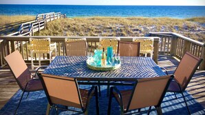 Una terraza con mesa y sillas frente a la playa.