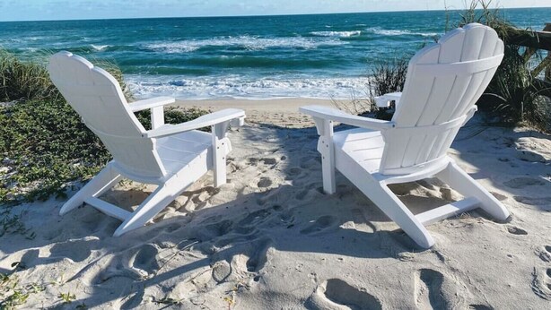 Two white Adirondack chairs facing a beach with the ocean in the background. - Rustic Beach Front Home - 6 Bedrooms - Private Beach Access - Large Groups (Melbourne Beach)