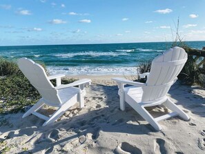 Two white Adirondack chairs facing a beach with the ocean in the background. - Rustic Beach Front Home - 6 Bedrooms - Private Beach Access - Large Groups (Melbourne Beach)