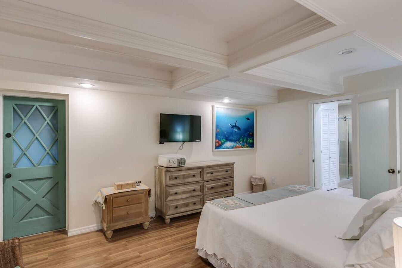 Ein Schlafzimmer mit Bett, Kommode, Fernseher und einem Gemälde.