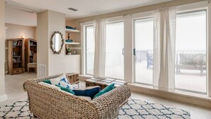 A cozy living room with a wicker sofa, a small table, and a bookshelf. - Rustic Beach Front Home - 6 Bedrooms - Private Beach Access - Large Groups (Melbourne Beach)