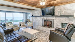 A spacious living room with a fireplace, leather sofas, and a large TV mounted on the wall. - Rustic Beach Front Home - 6 Bedrooms - Private Beach Access - Large Groups (Melbourne Beach)