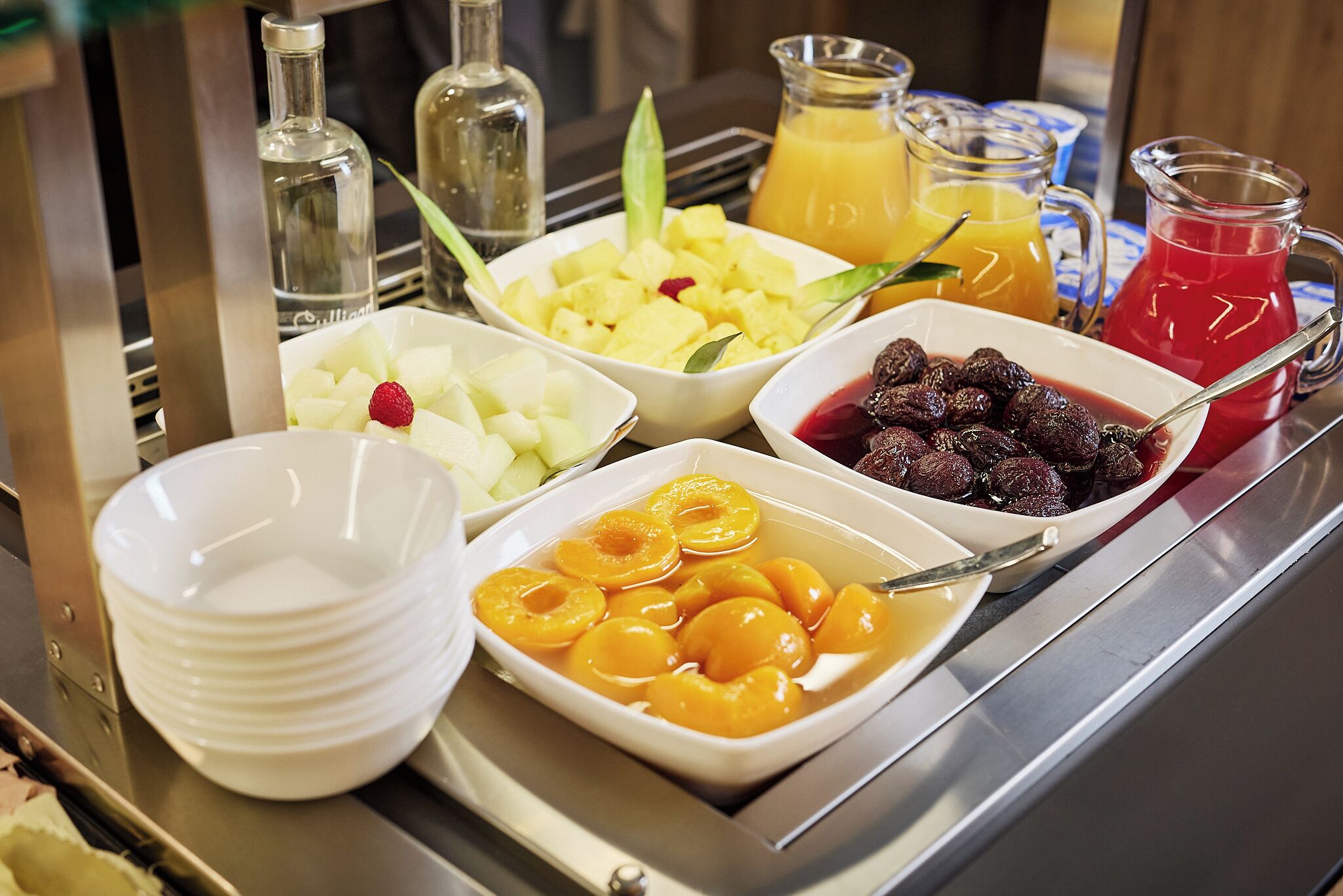 Un bufé de desayuno con diversas frutas y bebidas.