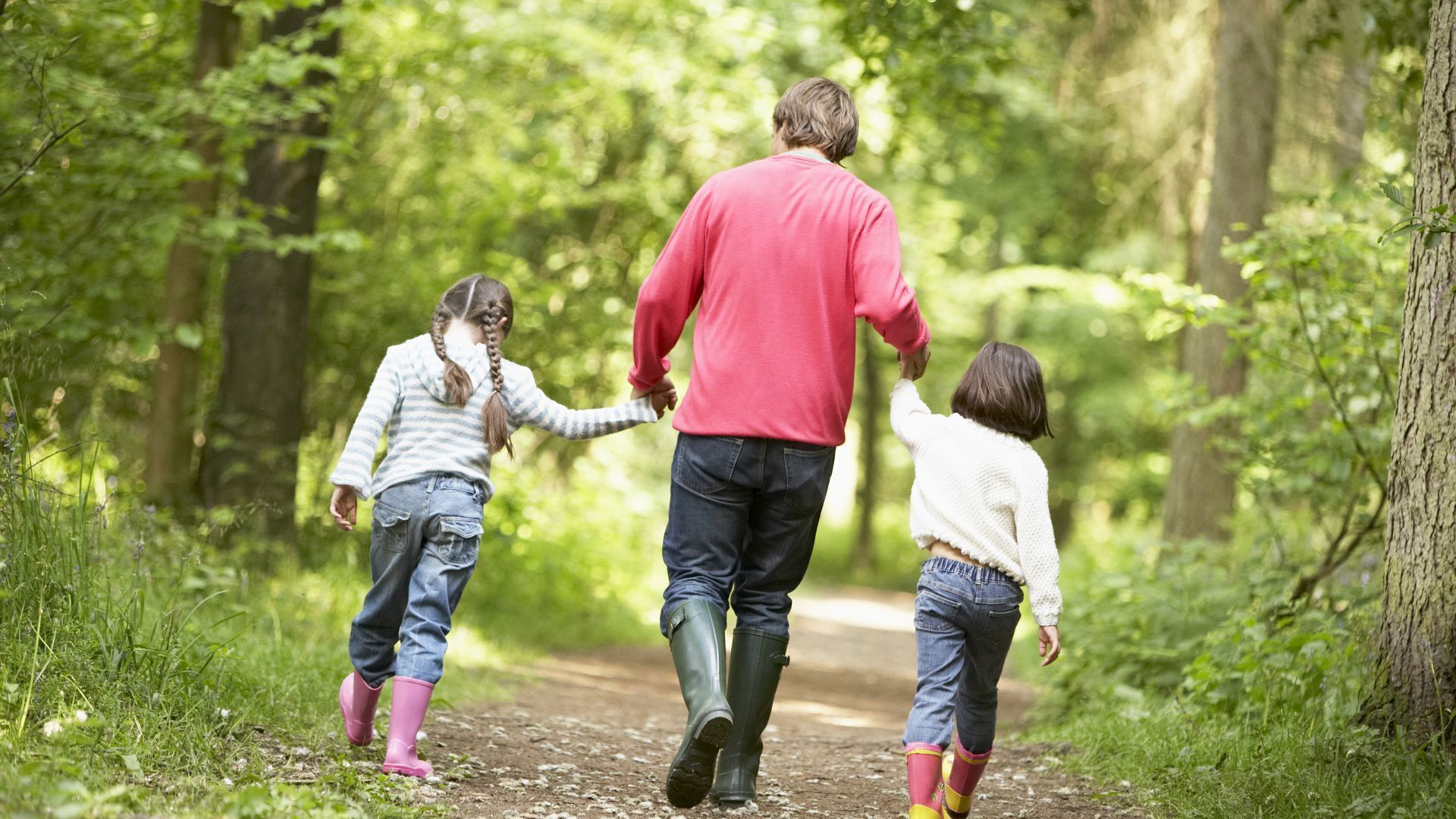 A family walking on a dirt path in a wooded area.