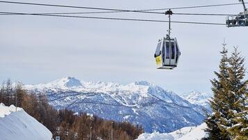 A road with a cable car in the background, snow-covered landscape, and mountains.