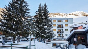 A snow-covered mountain resort with a bar and restaurant, a parking area, and a building with balconies overlooking the snowy landscape. - Hotel Hermitage (Sestriere)