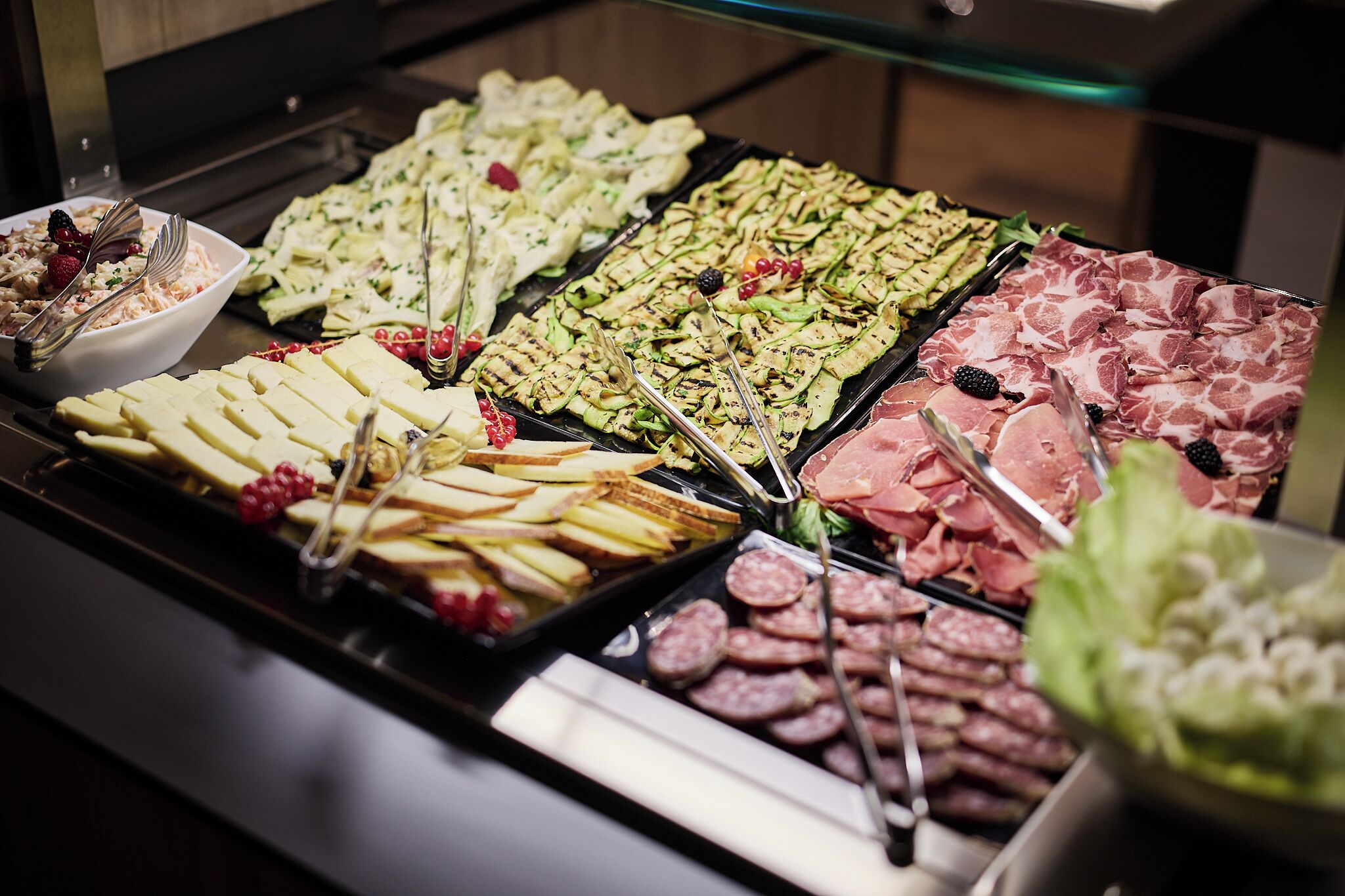 A buffet with various food items including meats, cheeses, and fruits.