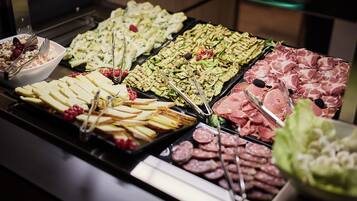 A buffet with various food items including meats, cheeses, and fruits.