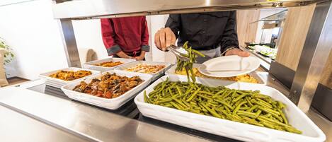Un buffet proposant divers plats, notamment des haricots verts et d’autres aliments préparés.