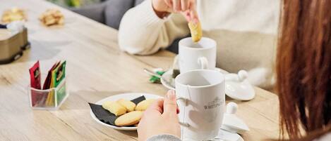 A wooden table with a plate of cookies and a cup of tea.