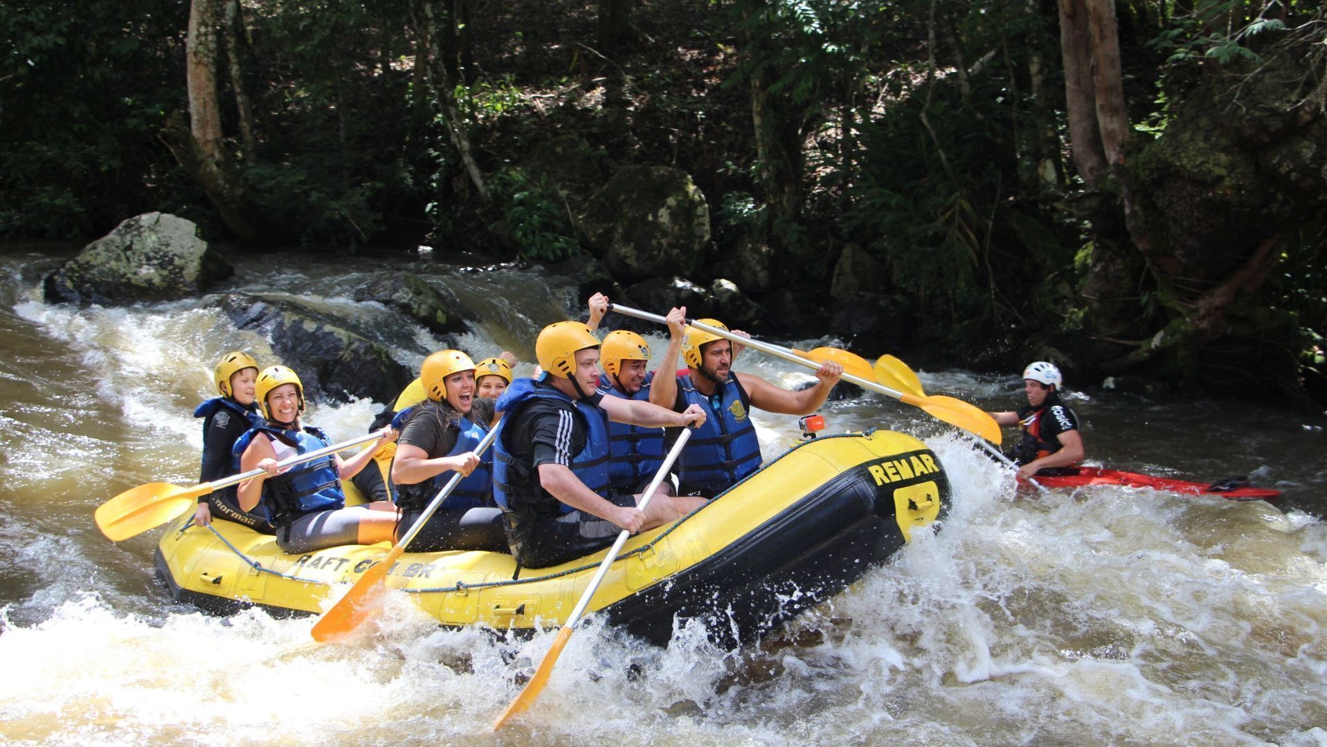 Een groep mensen in een gele rubberboot die over een rivier vaart.