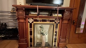 A fireplace with a decorative mantel, a television above it, and a patterned rug in front.