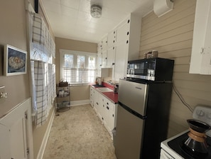 A kitchen with white cabinets, a stainless steel refrigerator, a microwave, and a stove.