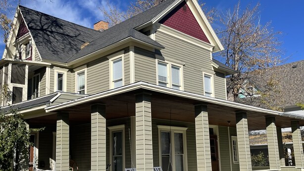 A two-story house with a covered porch and a red roof.